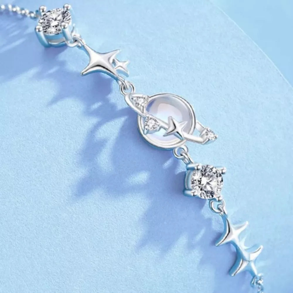 Silver celestial bracelet with stars, planet charm, and cubic zirconia accents.