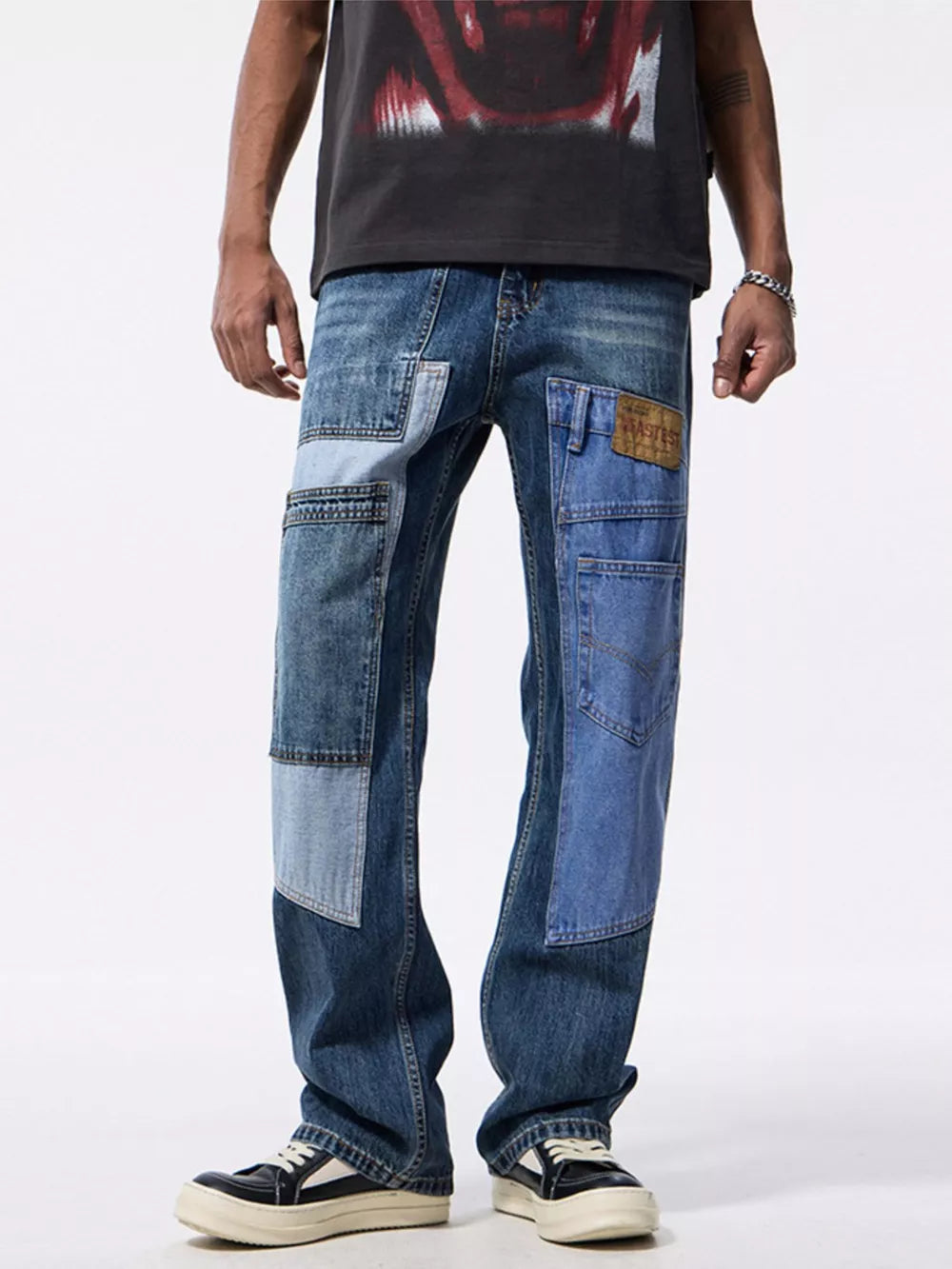 Men's relaxed fit jeans with distinctive blue denim patchwork and distressed details.