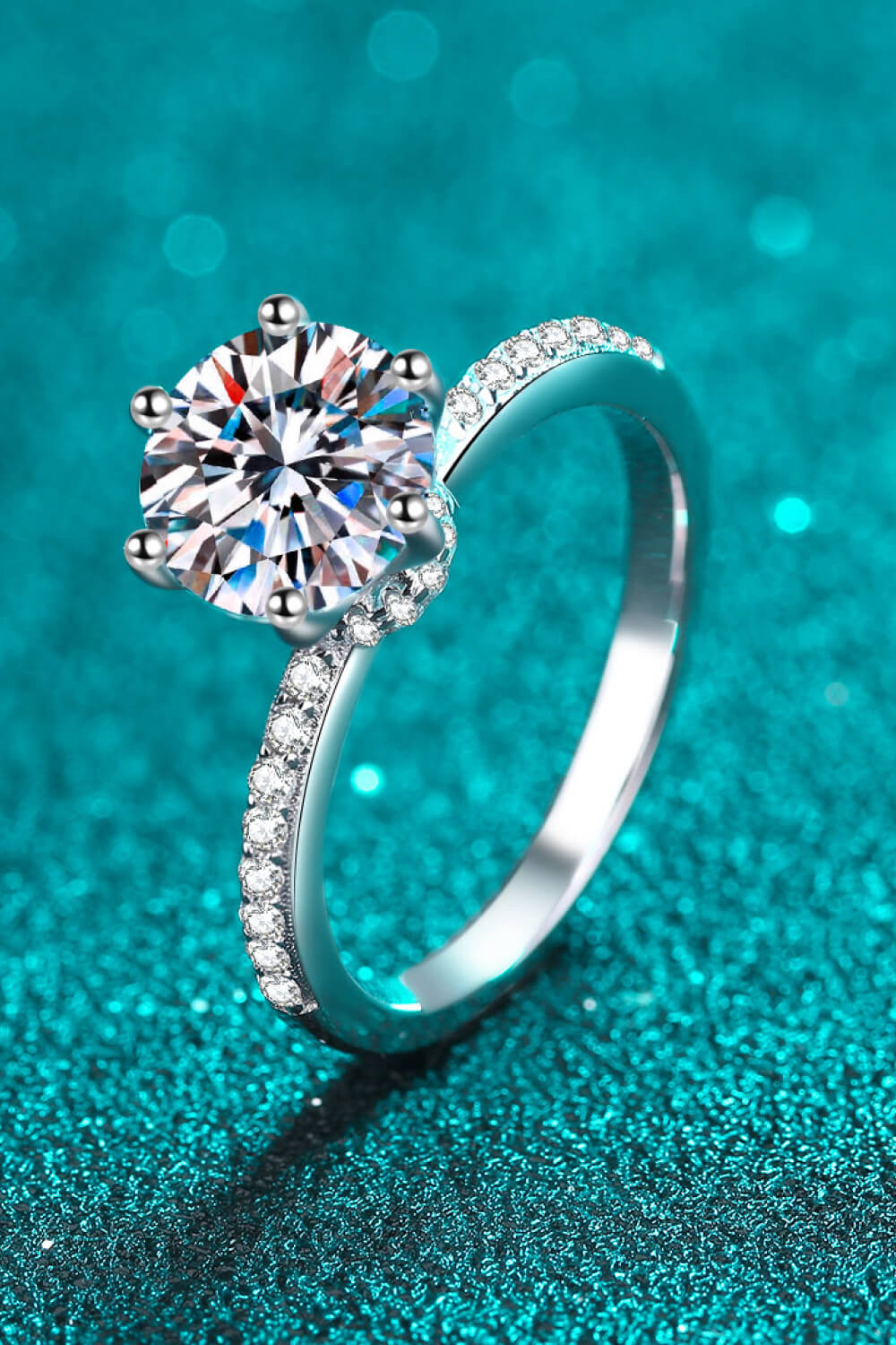 Silver moissanite ring with pavé band and six-prong setting.