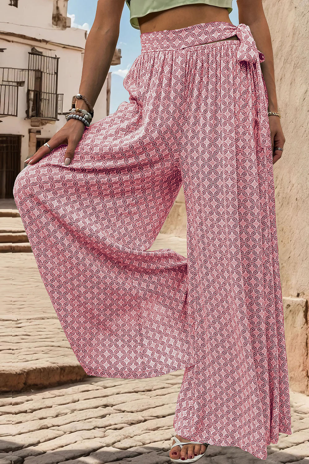 Pink geometric print wide-leg palazzo trousers with a tie waist detail.