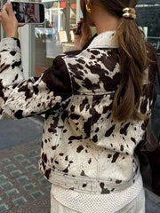 Buttoned collared jacket in cow print with a button front and long sleeves.