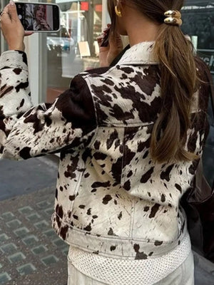Buttoned collared jacket in cow print with a button front and long sleeves.