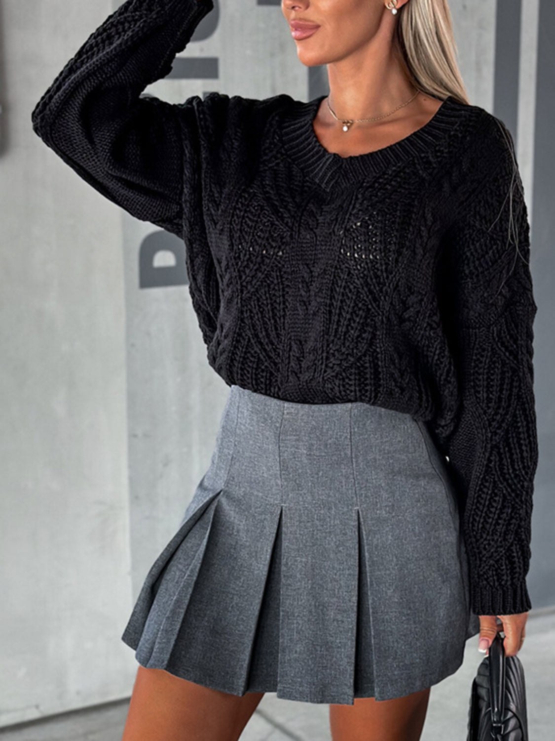 Black cable knit V-neck sweater with relaxed fit and textured pattern.