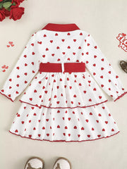 White tiered baby dress with red hearts, red collar, cuffs, and belt.