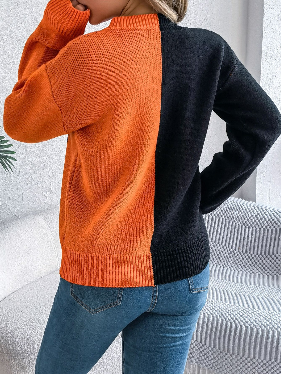 Split-face orange and black knit sweater with ribbed cuffs and hem.