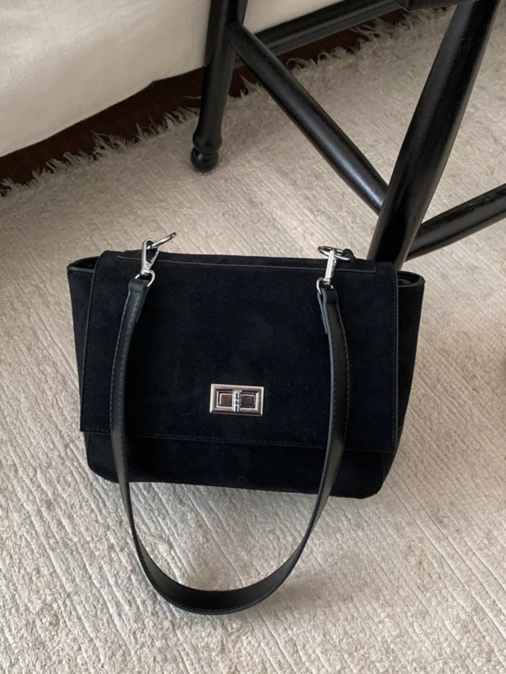Black suede crossbody bag with flap closure and silver hardware.