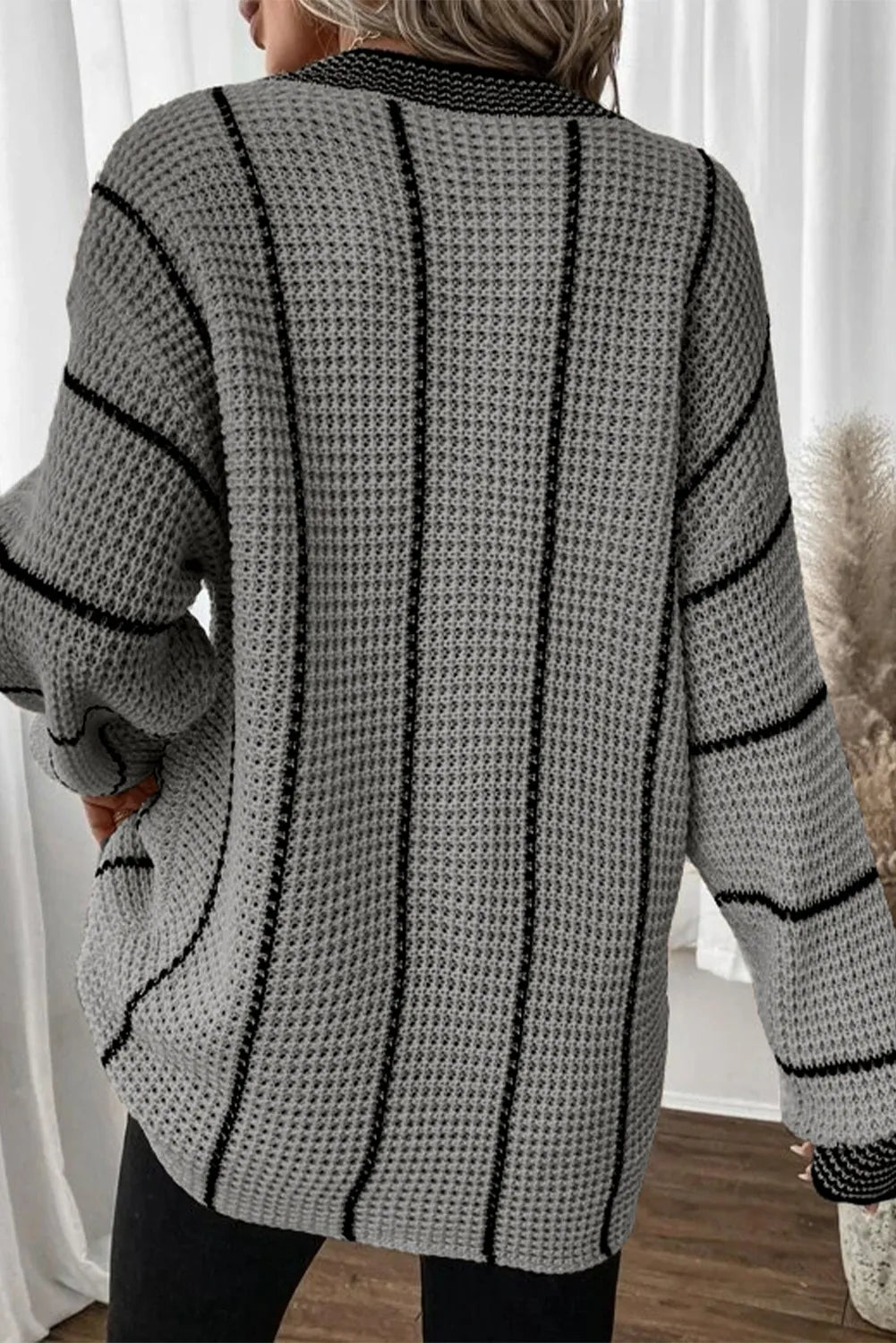 Gray knit oversized V-neck dress with black vertical stripes and waffle texture.