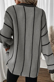 Gray knit oversized V-neck dress with black vertical stripes and waffle texture.
