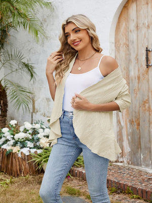 Tan eyelet cascade cardigan with open front and waterfall hem, styled with a white tank top and jeans.