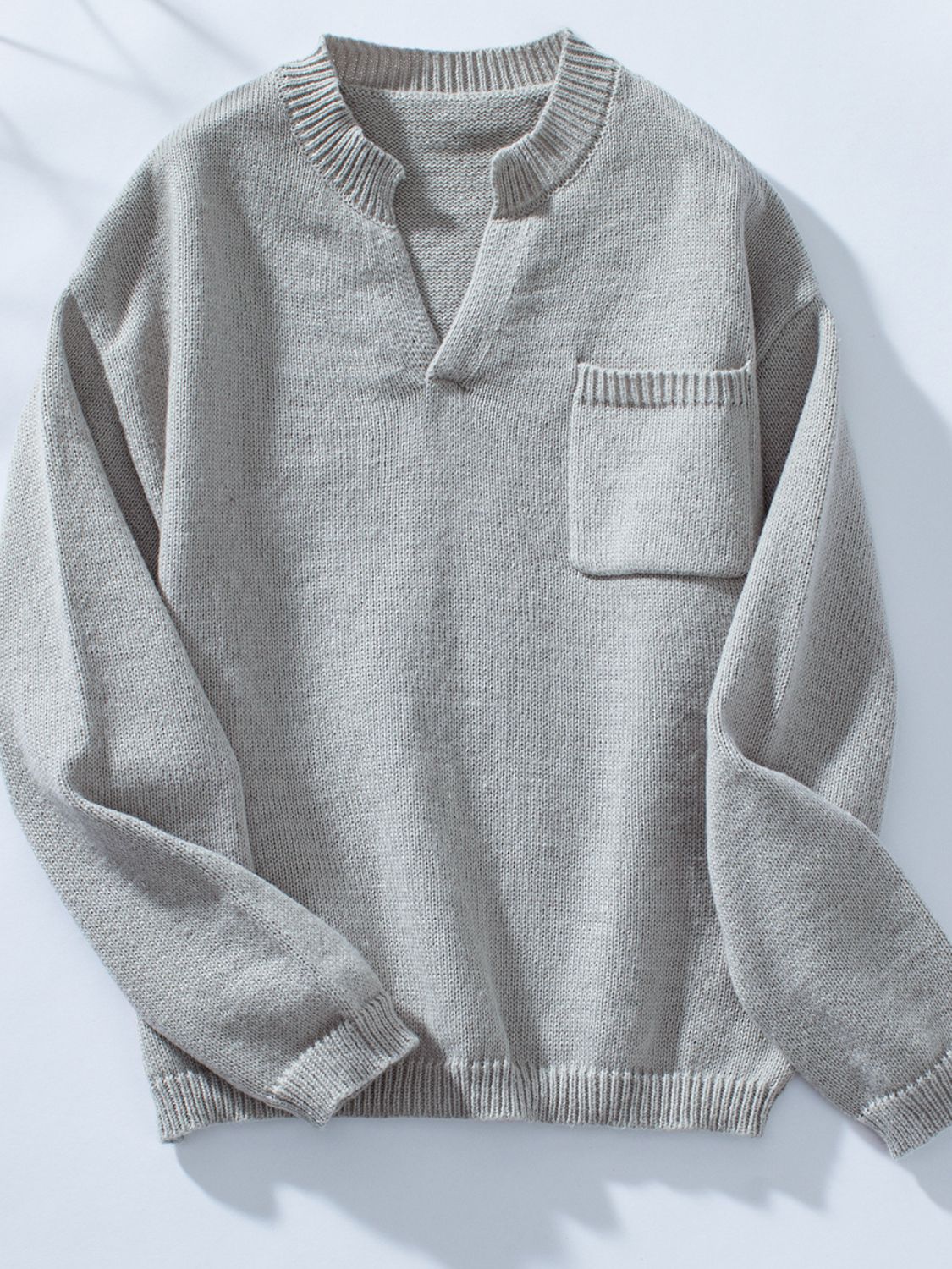 Gray knit sweater with notched neckline and chest pocket.