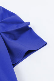 Royal blue puffed sleeve jumpsuit detail showing hem and fabric texture.