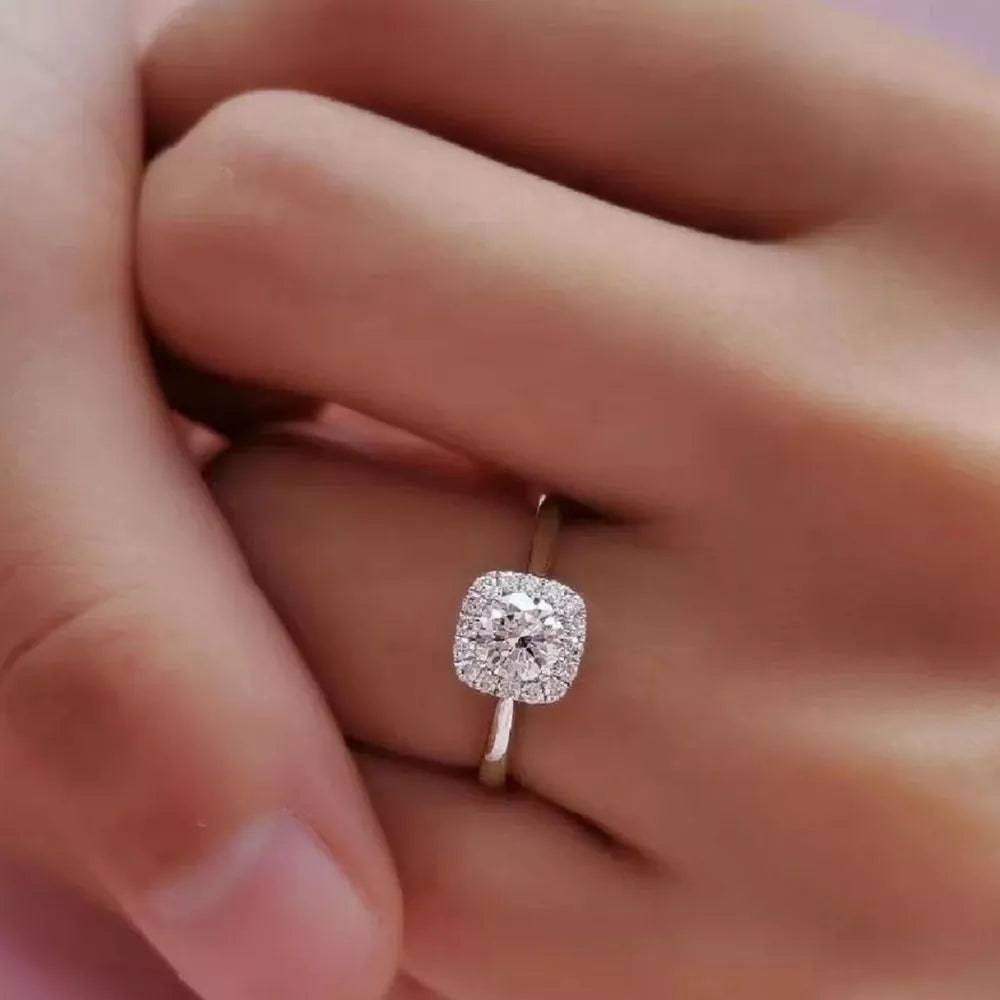 Elegant moissanite and sterling silver ring with a brilliant cushion-cut center stone and halo.