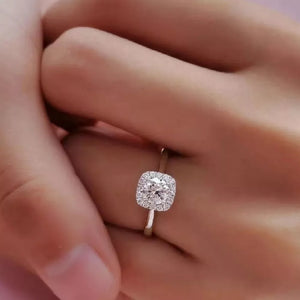 Elegant moissanite and sterling silver ring with a brilliant cushion-cut center stone and halo.