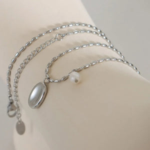 Silver oval medallion and pearl accent necklace with a beaded chain.