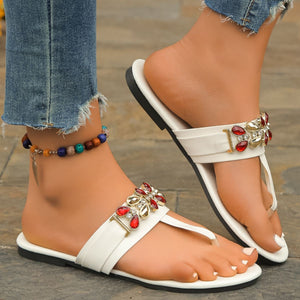 White jeweled toe-post flat sandals with red and clear rhinestones.