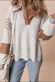 White waffle knit polo with leopard print collar and sleeves, and brown elbow patches.