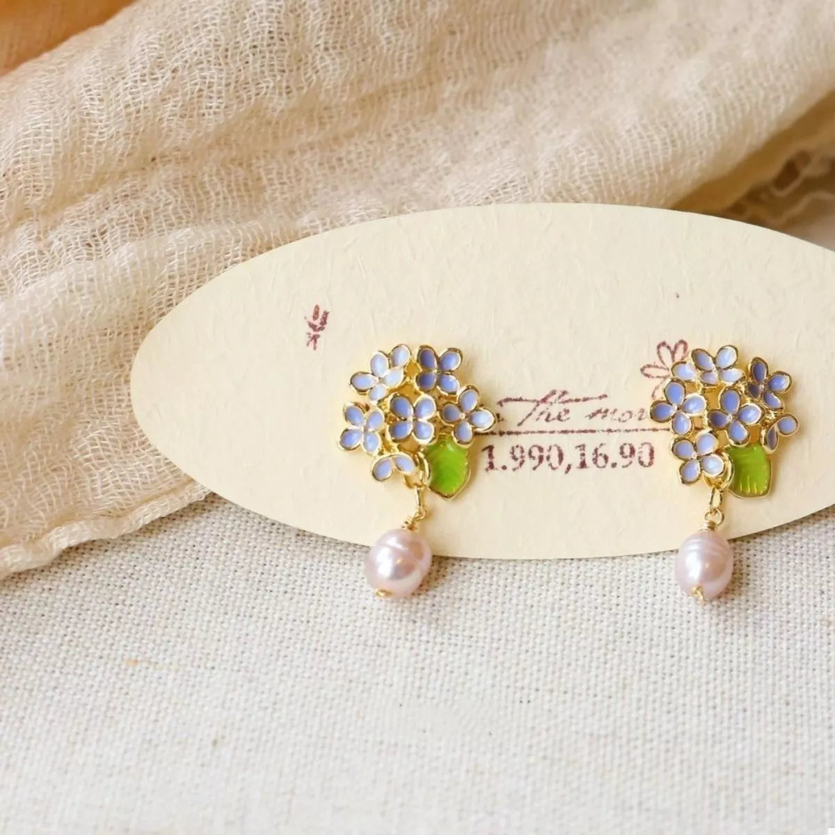 Floral pearl drop earrings with light blue flowers and pink pearls.