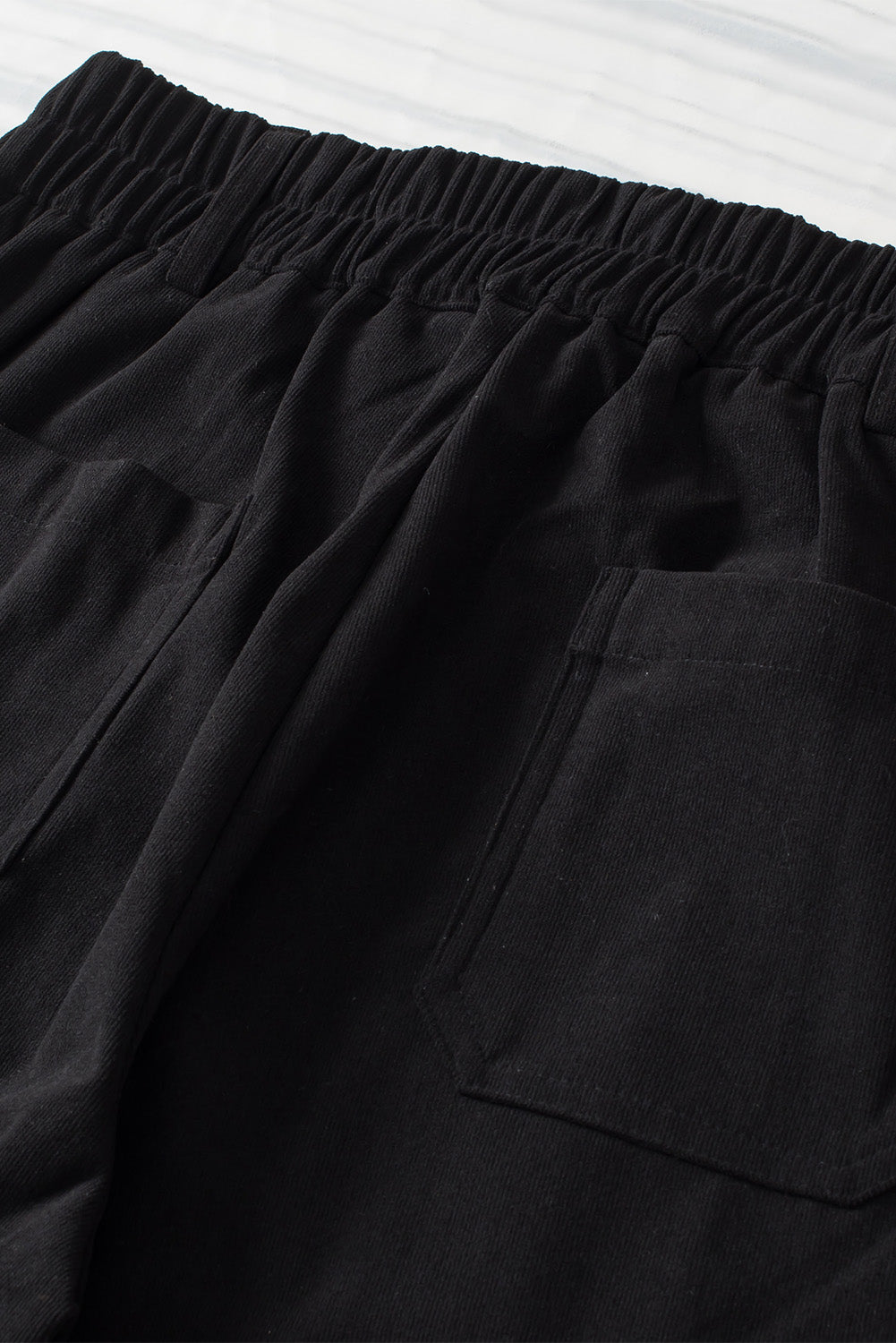 Black seamed front wide leg trousers with elastic waistband and patch pockets.