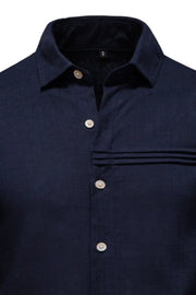 Navy linen shirt with buttoned collar and pleated pocket detail.