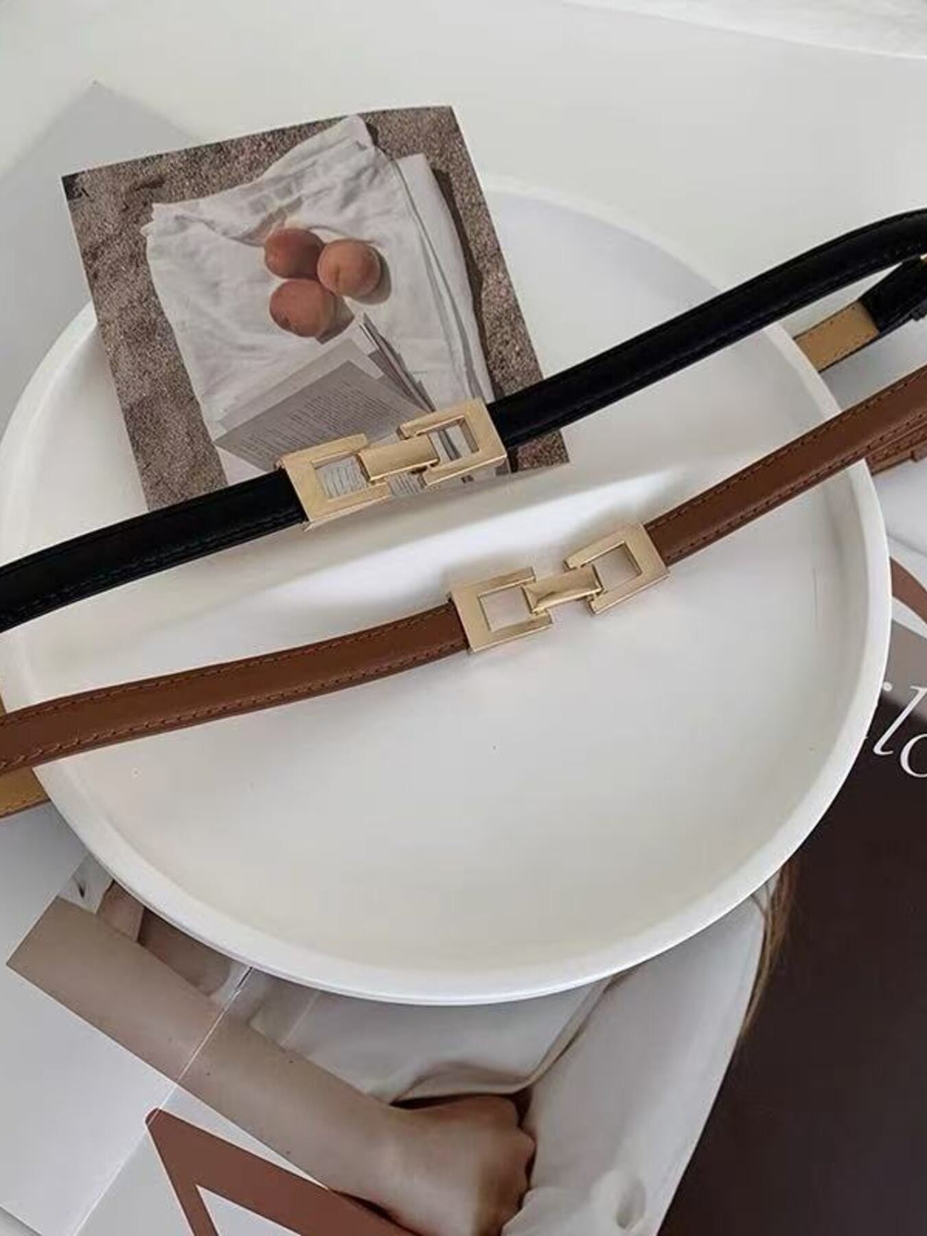 Elegant cowhide leather belts in black and brown with gold buckle detail.