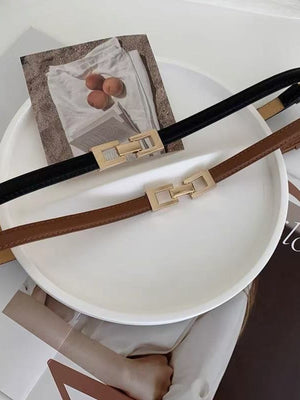 Elegant cowhide leather belts in black and brown with gold buckle detail.