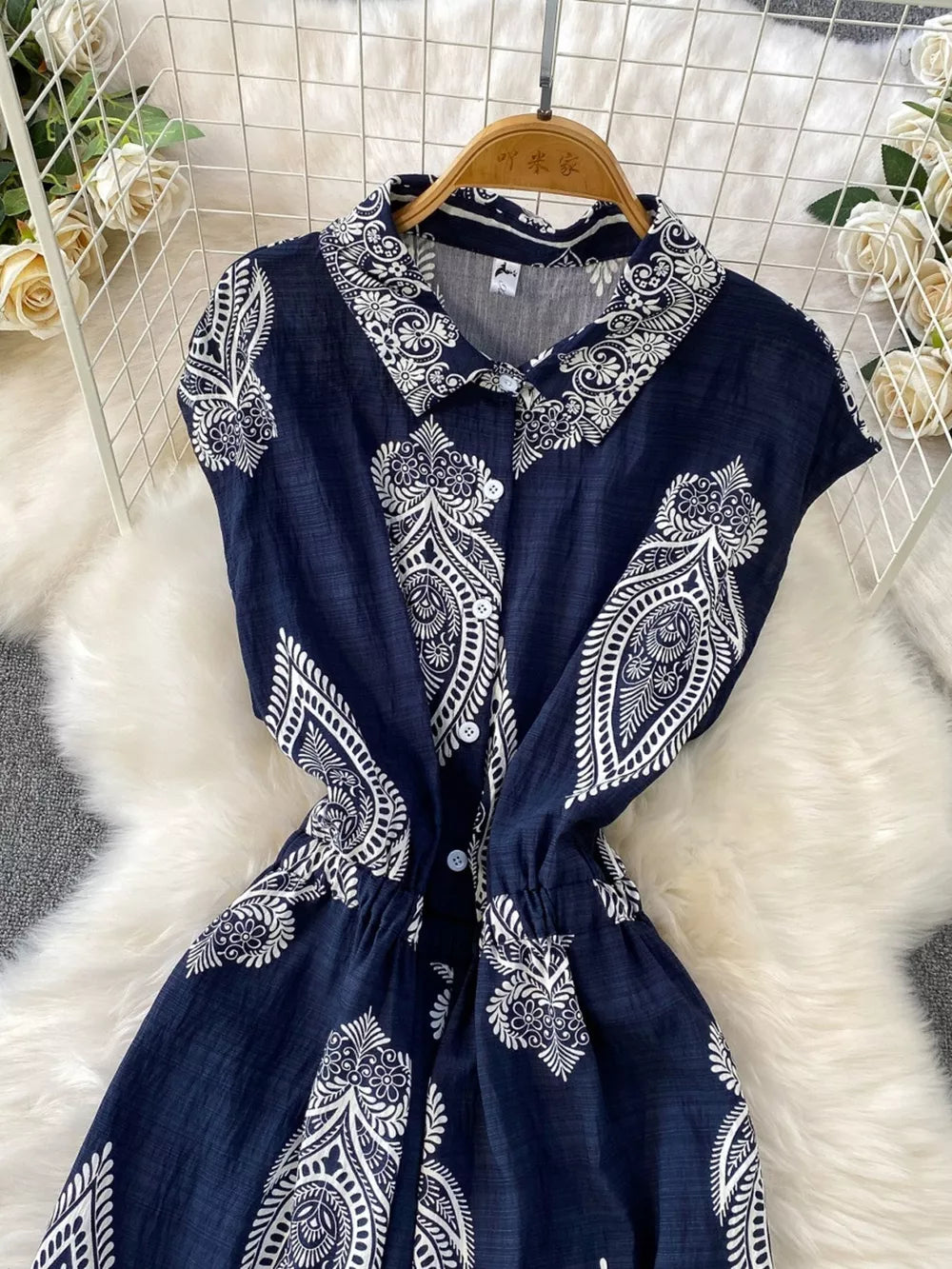 Navy blue collared button-down romper with white paisley print and drawstring waist.