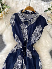 Navy blue collared button-down romper with white paisley print and drawstring waist.