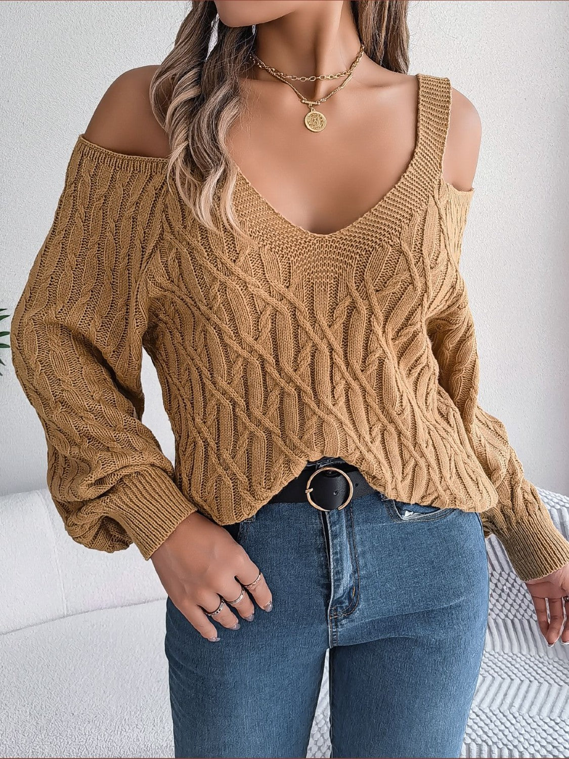 Knit cold shoulder sweater in taupe with cable knit pattern and V-neckline.