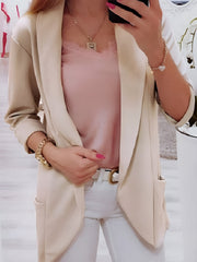 Open-front beige blazer with rolled sleeves and pockets, styled with a pink cami.