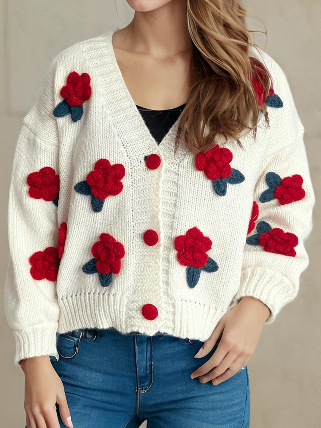 White knit cardigan with red rose appliqués and buttons, V-neck, long sleeves.