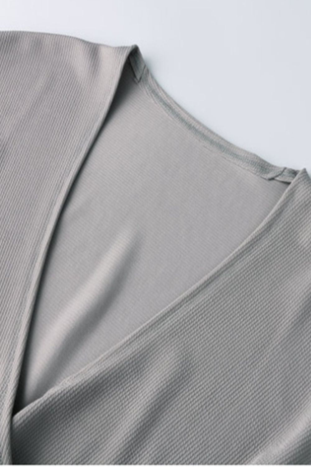 Gray Dawn ribbed knit wrap-effect blouse with V-neck detail.