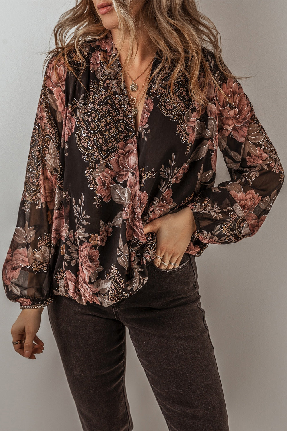 Black floral print surplice blouse with blouson sleeves and a deep V-neck.