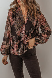 Black floral print surplice blouse with blouson sleeves and a deep V-neck.