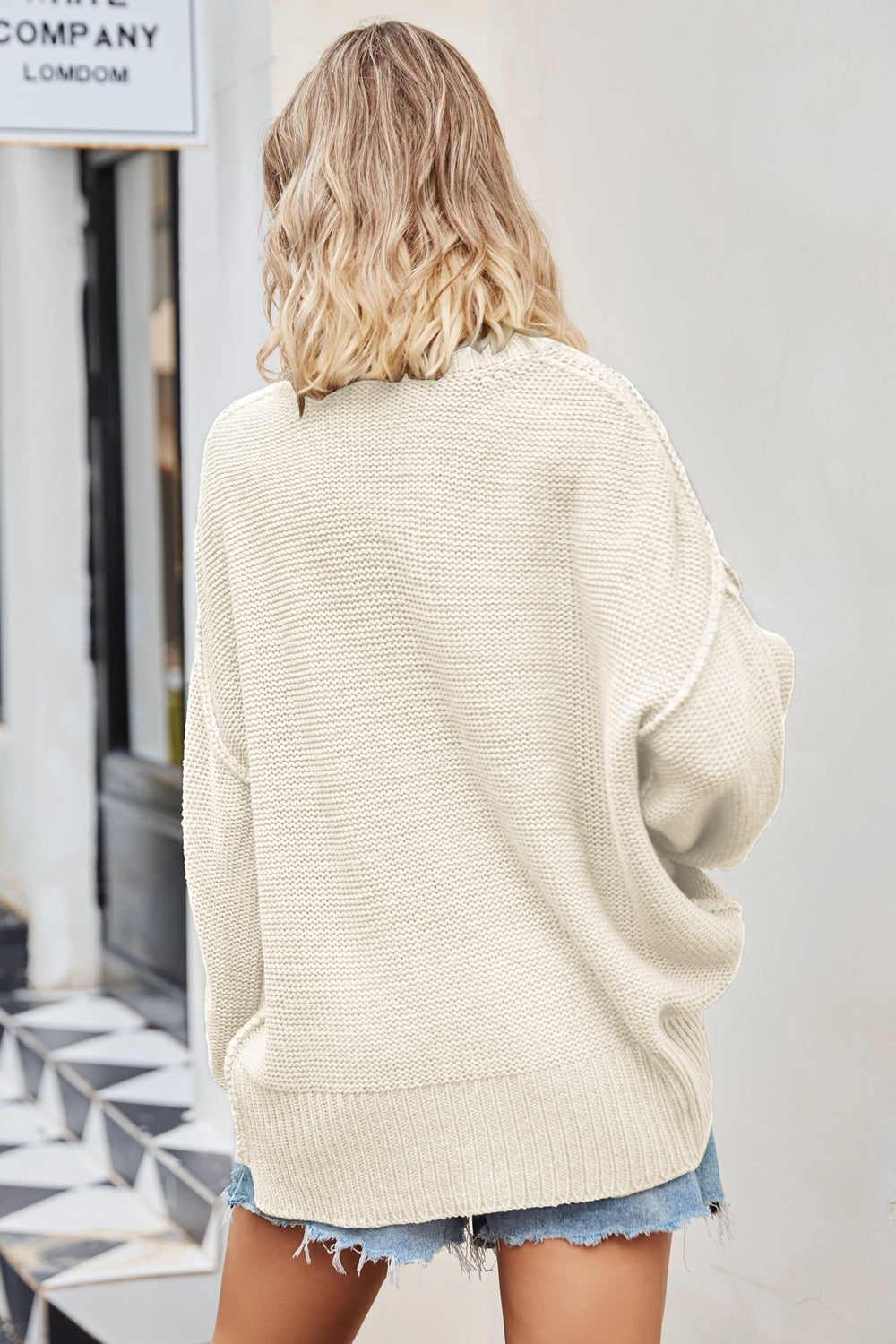 Oversized cream knit V-neck sweater with slouchy fit and ribbed hem.