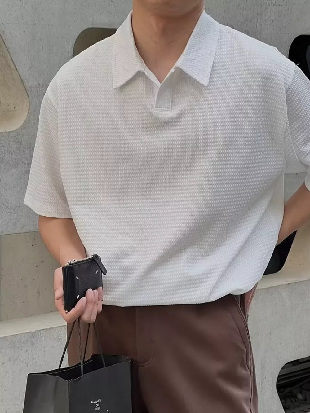 Men's white textured waffle knit polo shirt with button collar and short sleeves.