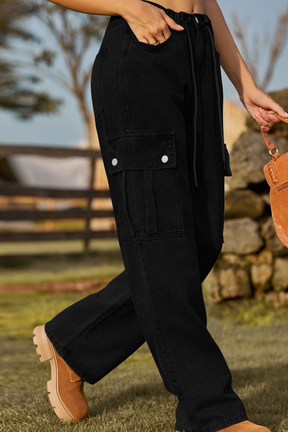 Black denim cargo pants with drawstring waist and button flap pockets.