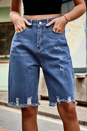 Medium wash denim bermuda shorts with frayed hem and distressed details.