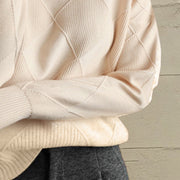 Ivory diamond knit turtleneck sweater with textured details and ribbed cuffs.