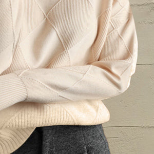 Ivory diamond knit turtleneck sweater with textured details and ribbed cuffs.