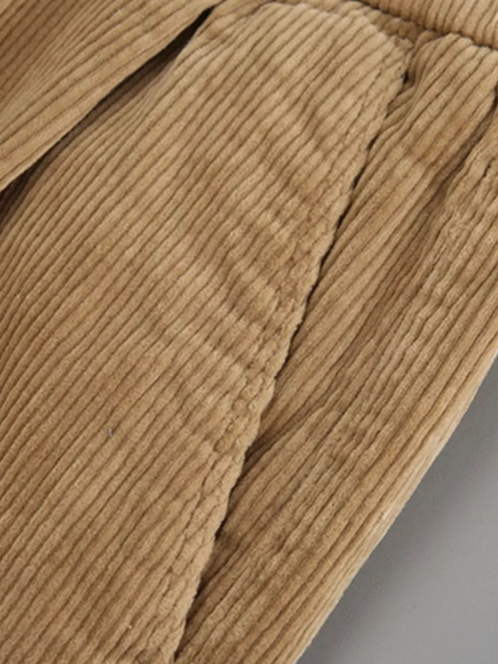 Khaki corduroy pants with subtle pleats and visible stitching detail.