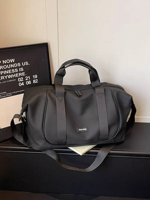 Black nylon travel duffle bag with adjustable strap and curved stitching detail.