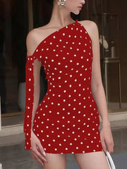 Red polka dot mini dress with asymmetrical neckline and single cold shoulder sleeve with bow detail.