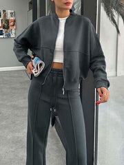 Dark gray bomber jacket with white crop top and matching wide-leg track pants