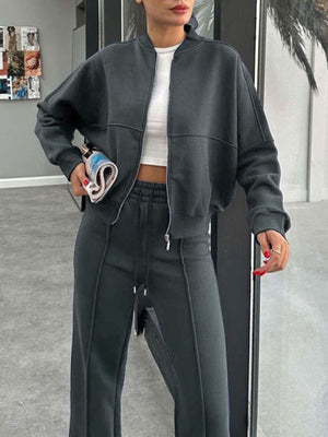 Dark gray bomber jacket with white crop top and matching wide-leg track pants
