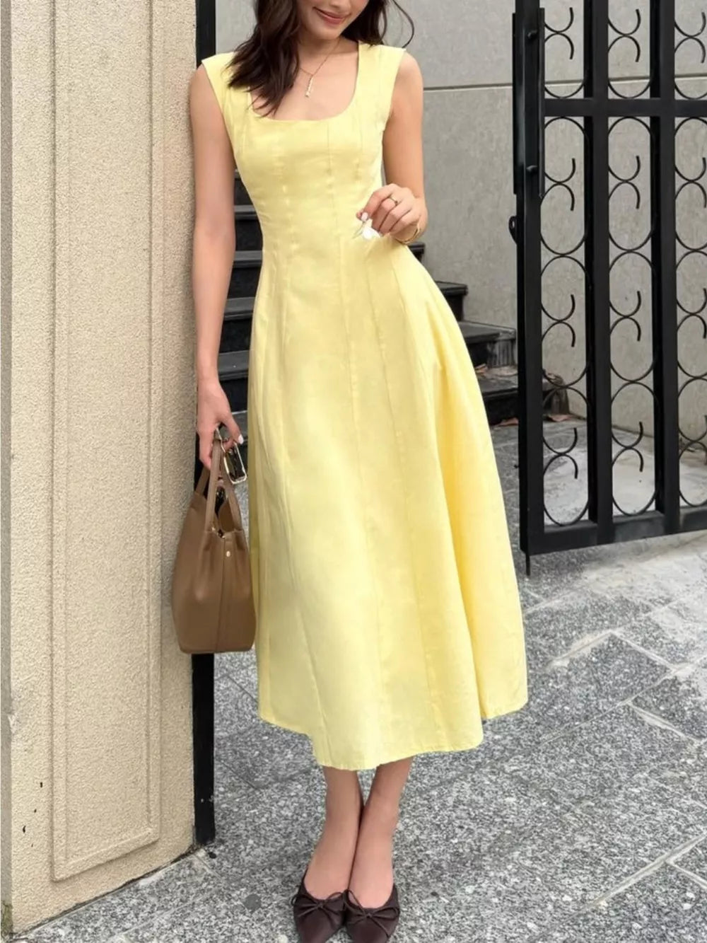 Sleeveless yellow a-line midi dress with square neckline and subtle vertical seams.