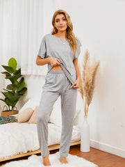 Gray loungewear set with asymmetric neckline top and relaxed fit pants.