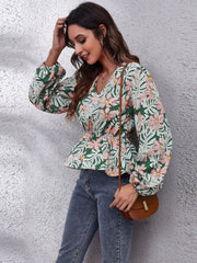 Floral peplum blouse with V-neck, gathered waist, and balloon sleeves in green with pink flowers.