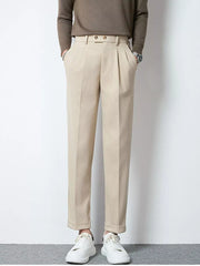 Men's khaki pleated dress pants with cuffed hems and double button closure.