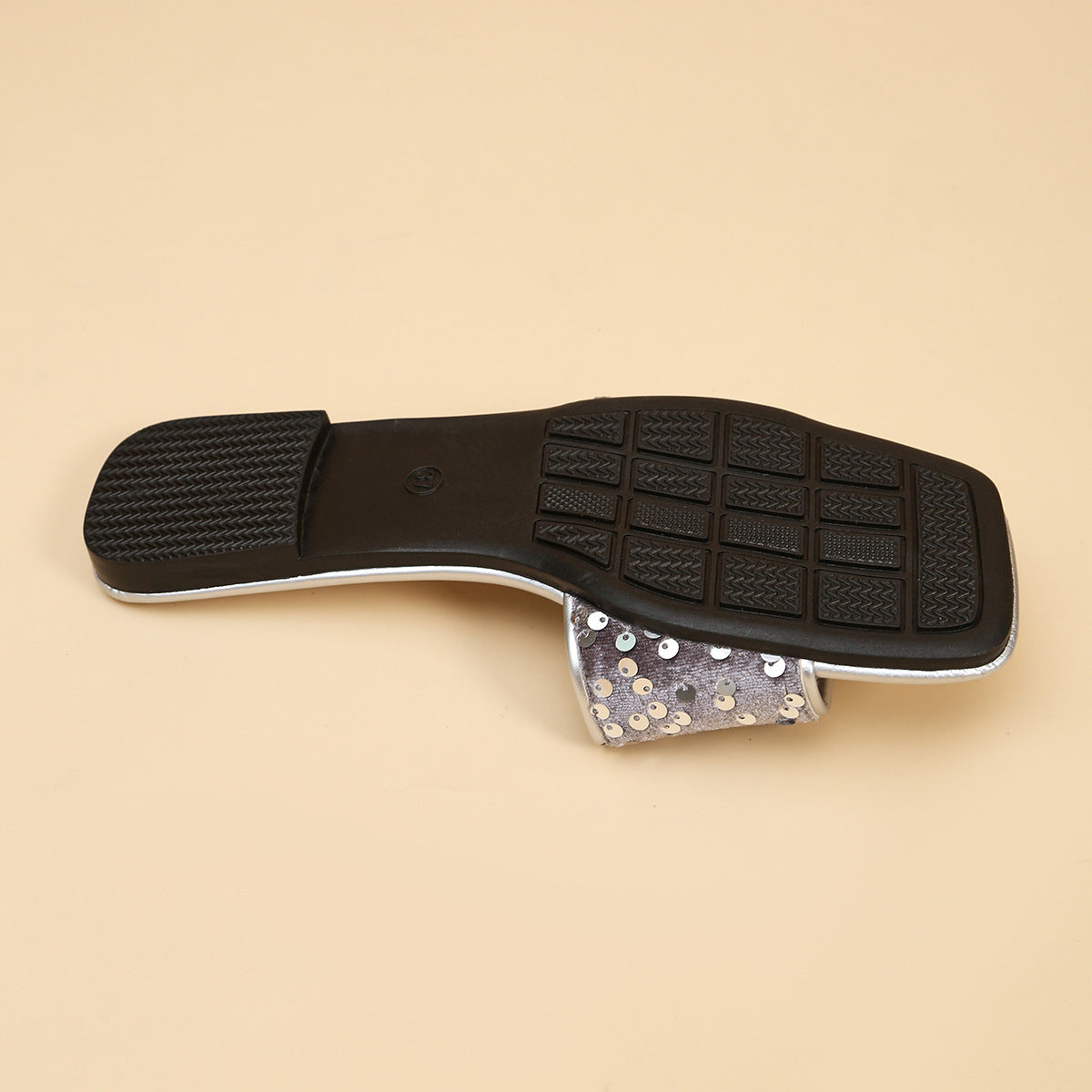 Silver sequined open-toe sandal with a black sole and textured tread.