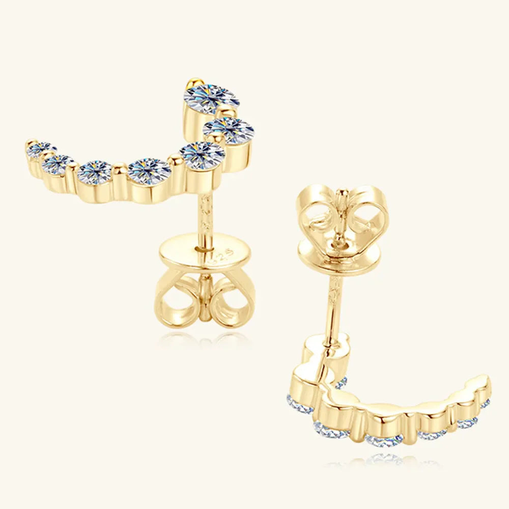 Gold celestial arc moissanite stud earrings with a curved design and sparkling stones.